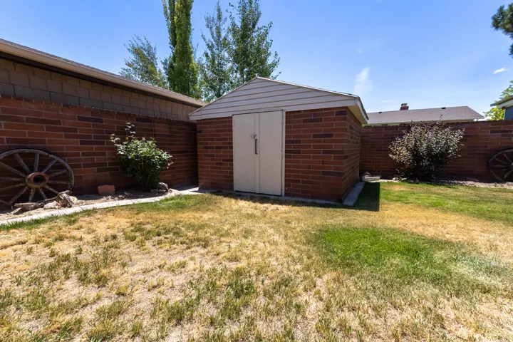 Brick storage shed with white siding roof trim, positioned on a concrete slab