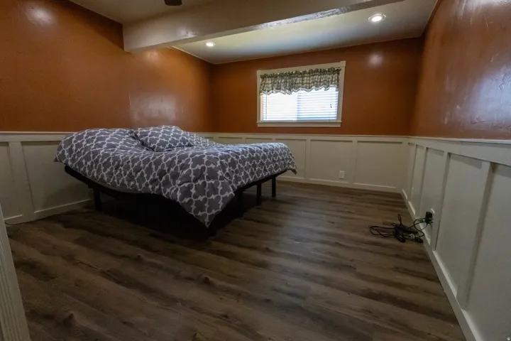Bedroom featuring wood-finish flooring, wainscoting, recessed lighting, and a window with blinds