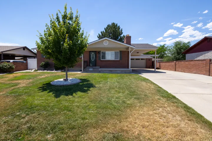 Brick exterior featuring a covered carport, attached garage, and a concrete driveway