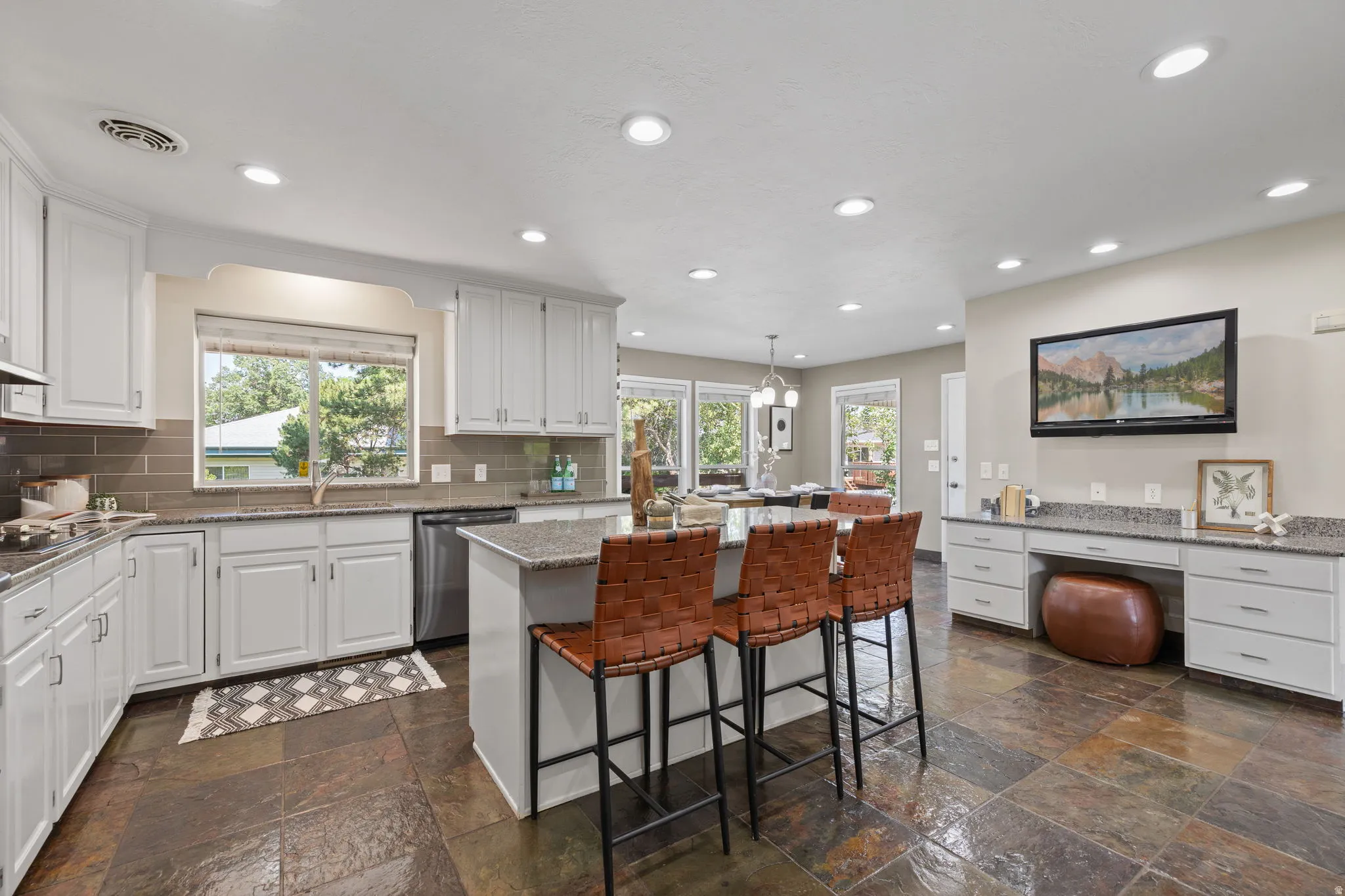Kitchen featuring slate tile flooring, white cabinetry, granite countertops, and a subway tile backsplash
