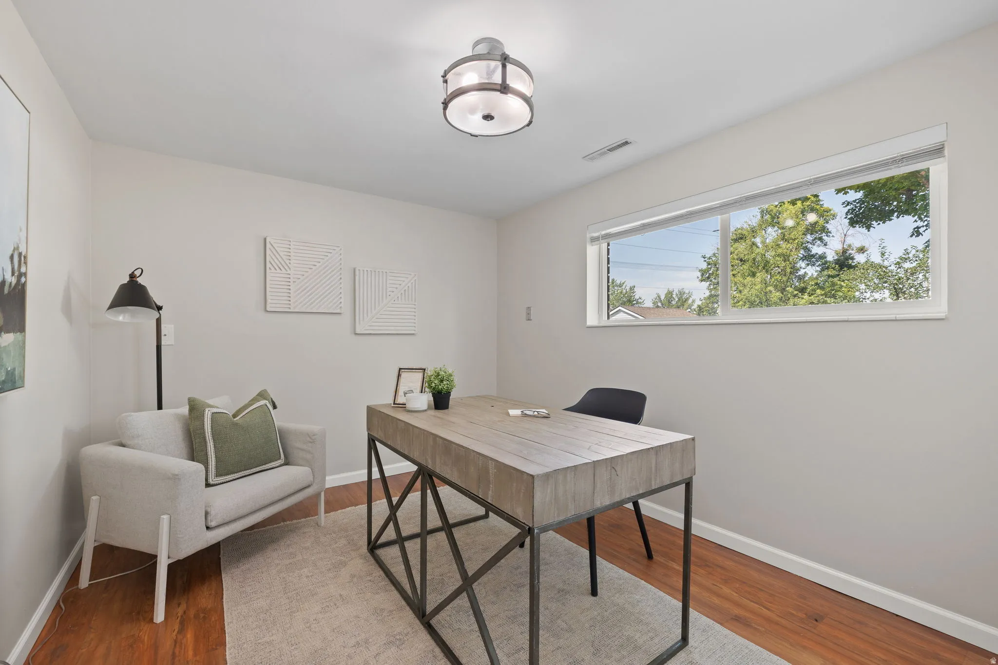 Versatile room with wood-finish flooring, a large horizontal window, and a contemporary flush-mount ceiling light