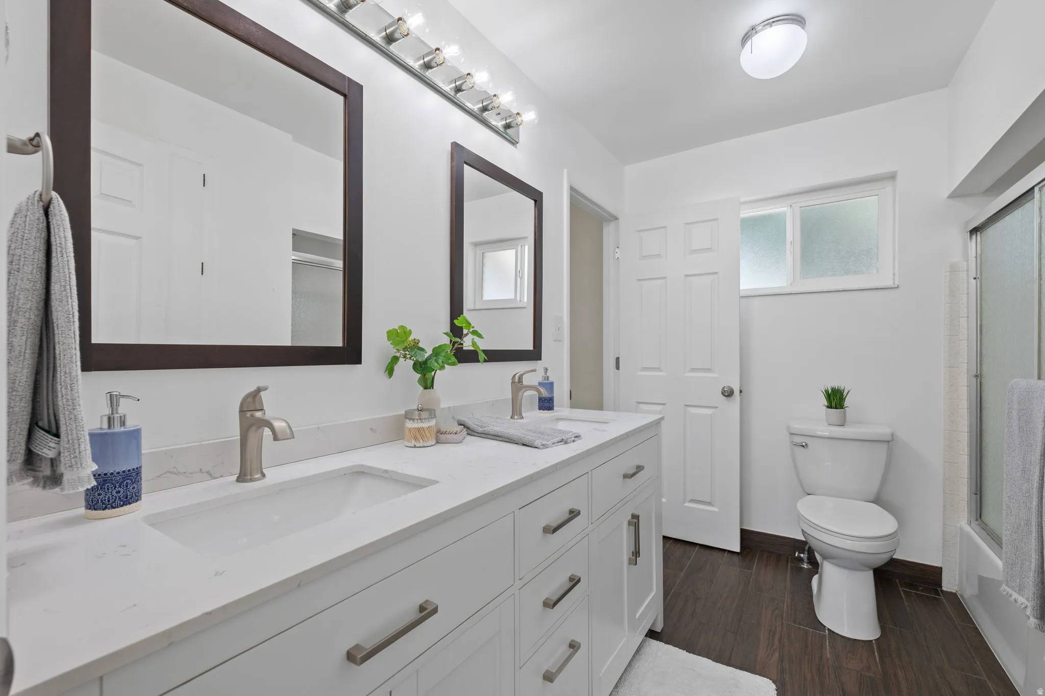 Bathroom featuring a dual vanity with white cabinetry, integrated sinks, and brushed nickel hardware