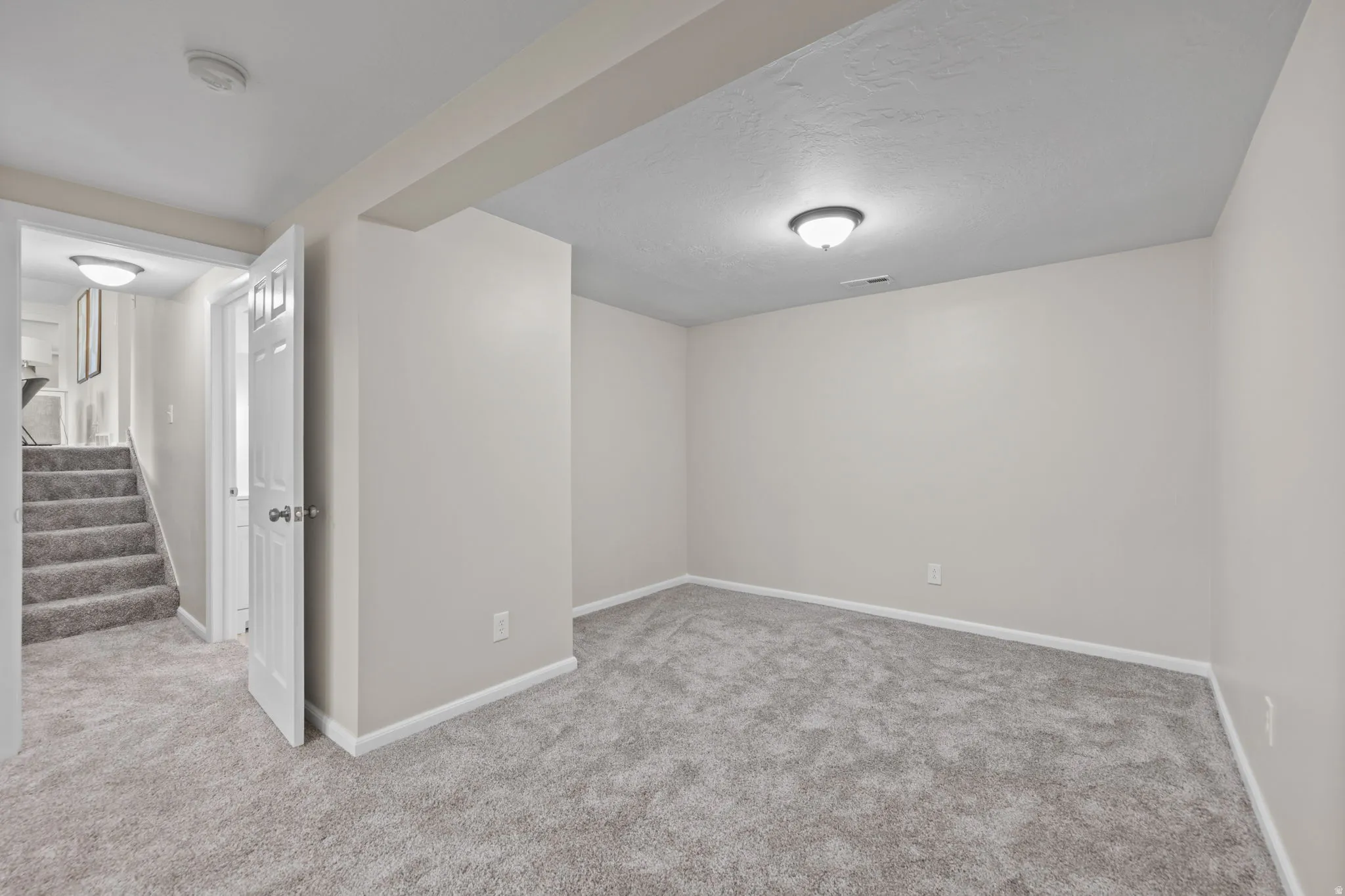Finished room featuring light gray walls, gray carpeting, white trim, and a ceiling-mounted light fixture