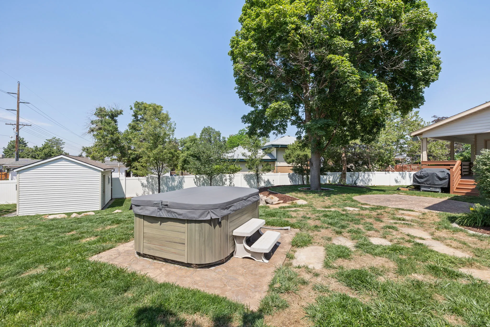 Backyard featuring a hot tub on a concrete pad, a detached storage shed with vinyl siding, and a wood deck with stairs
