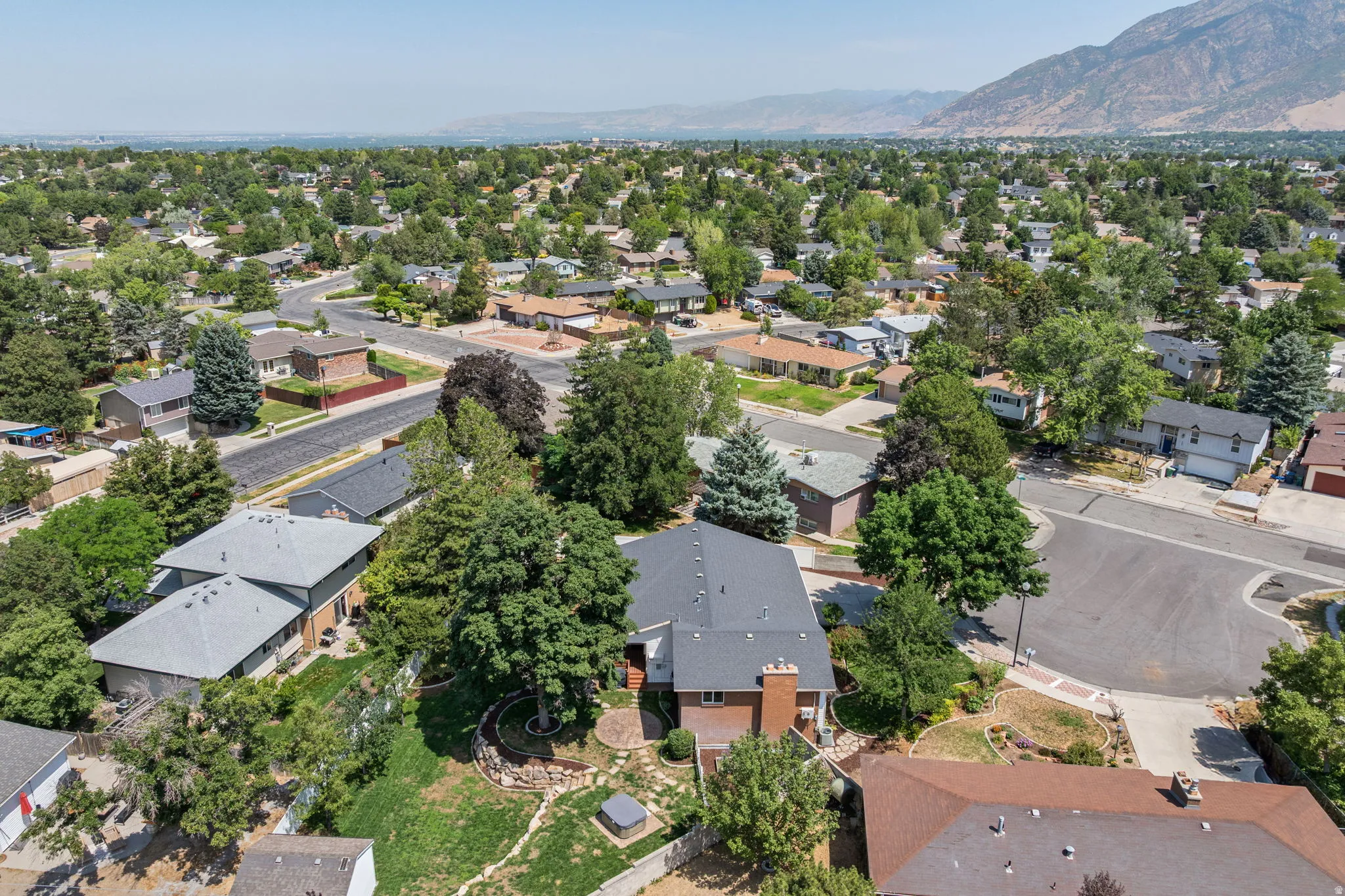 Expansive neighborhood setting with mature trees and mountain backdrop
