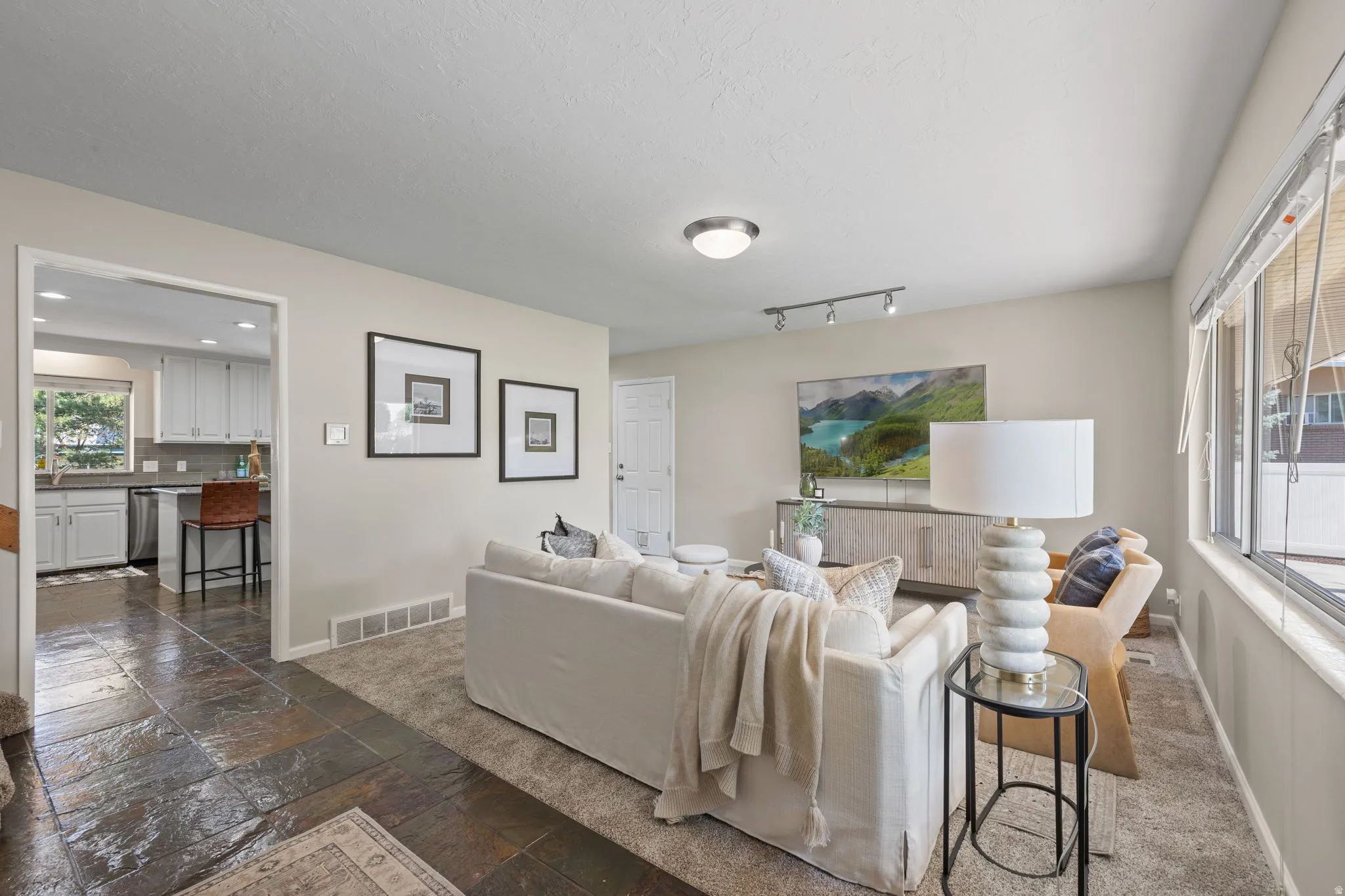 Expansive living area with neutral wall tones and a textured carpet