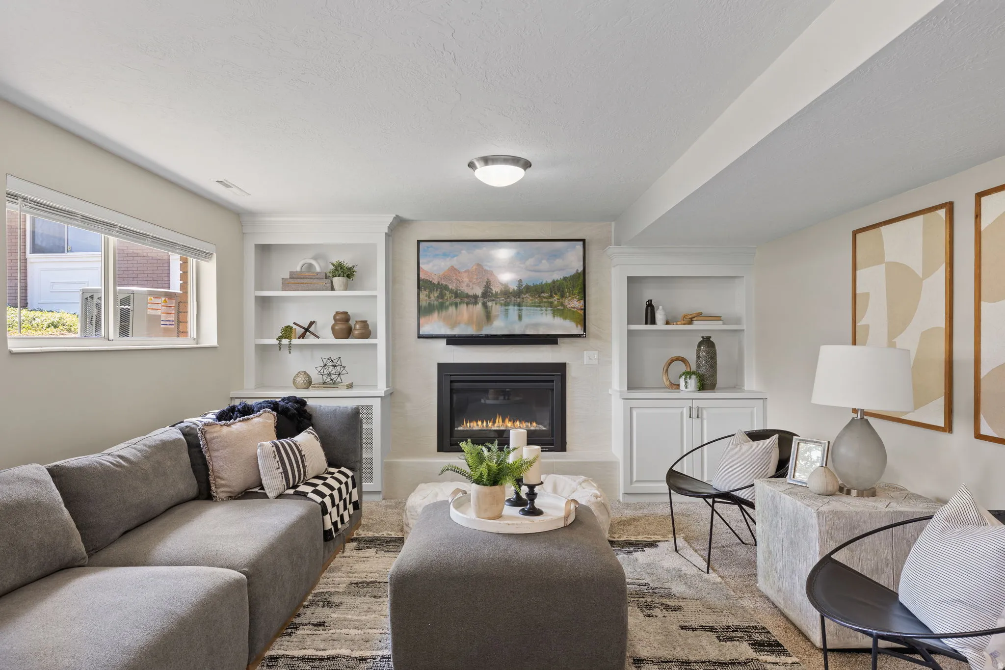 Living area featuring a built-in fireplace with a hearth, white built-in shelving, and recessed lighting