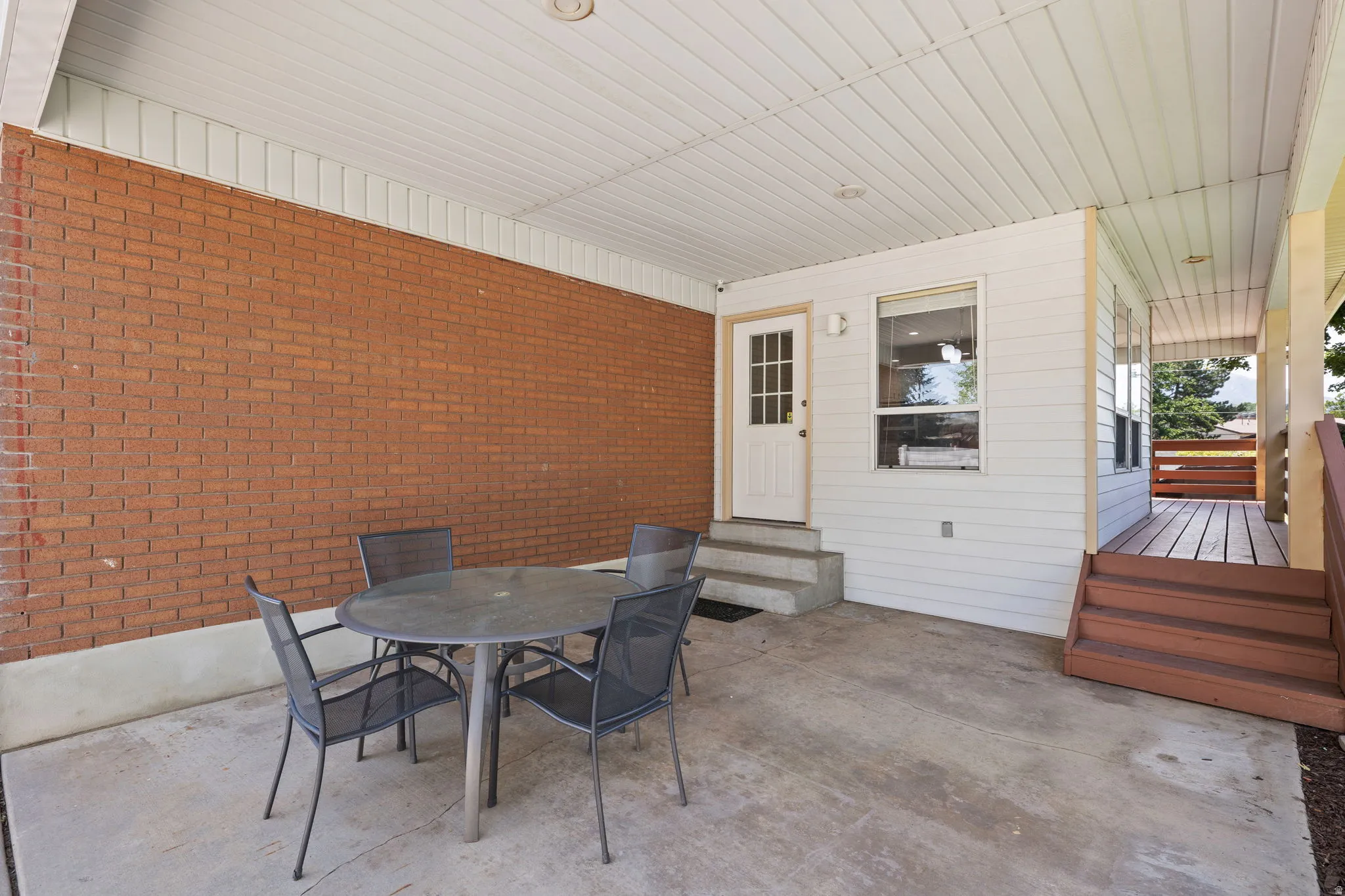 Covered concrete patio featuring a brick wall, white paneled ceiling, and recessed lighting