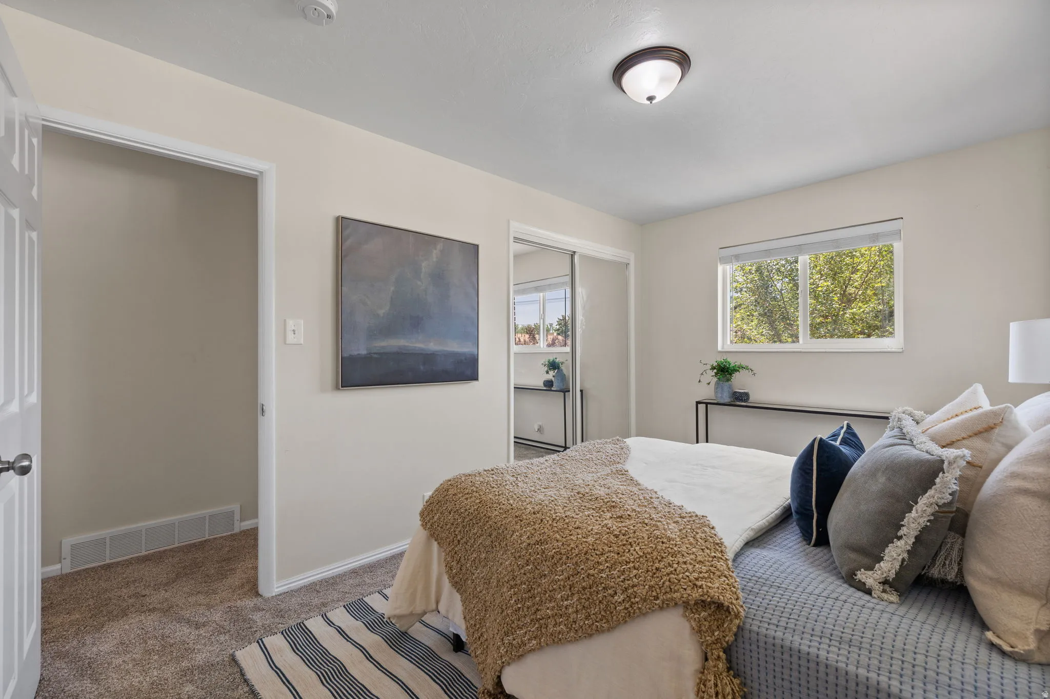 Bedroom featuring neutral wall paint, carpet flooring, a window with natural light, and a built-in closet with mirrored doors