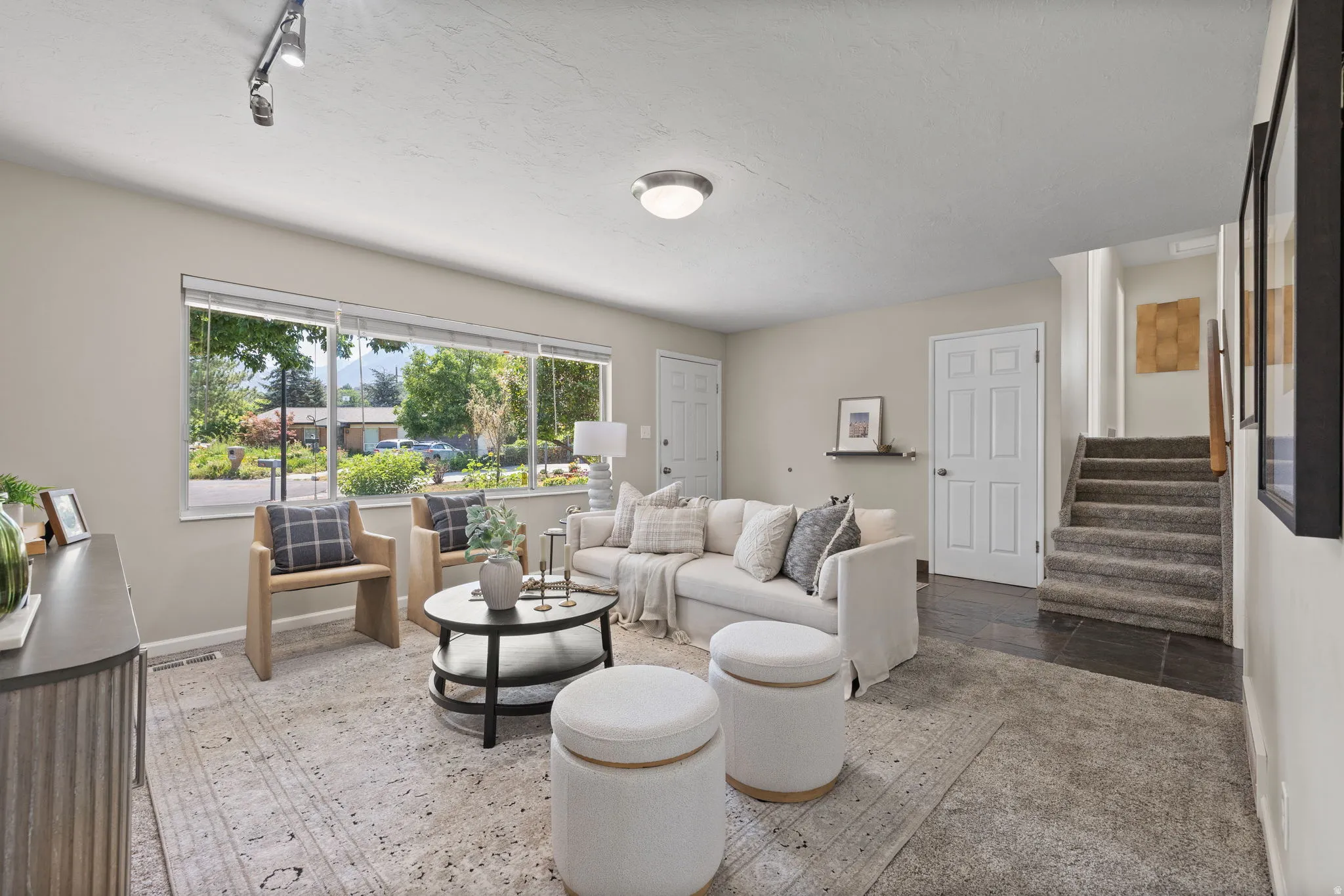 Living area featuring large windows, track lighting, and a neutral color palette