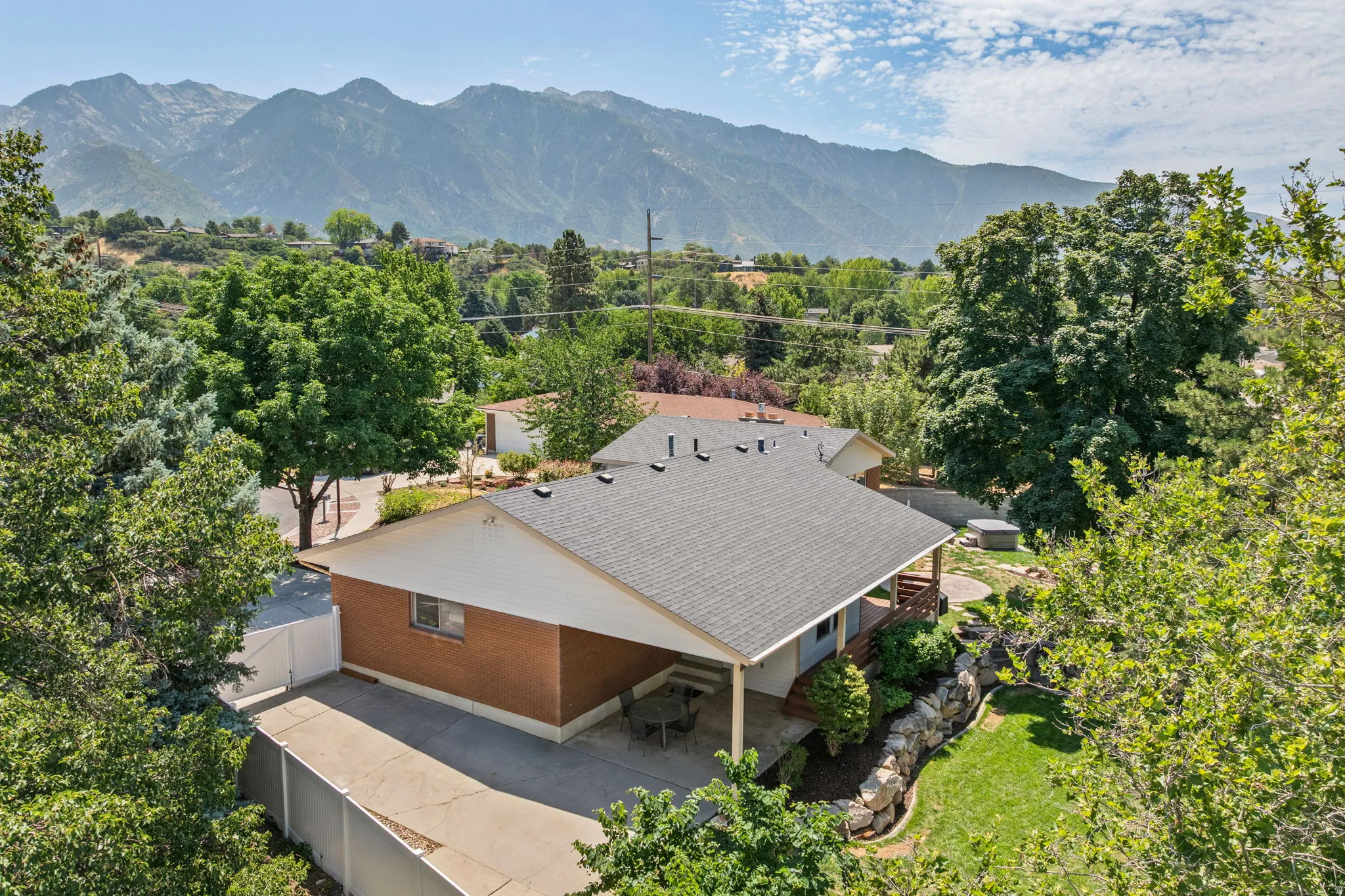 Brick exterior with a covered carport, private fenced yard, and tiered landscaping