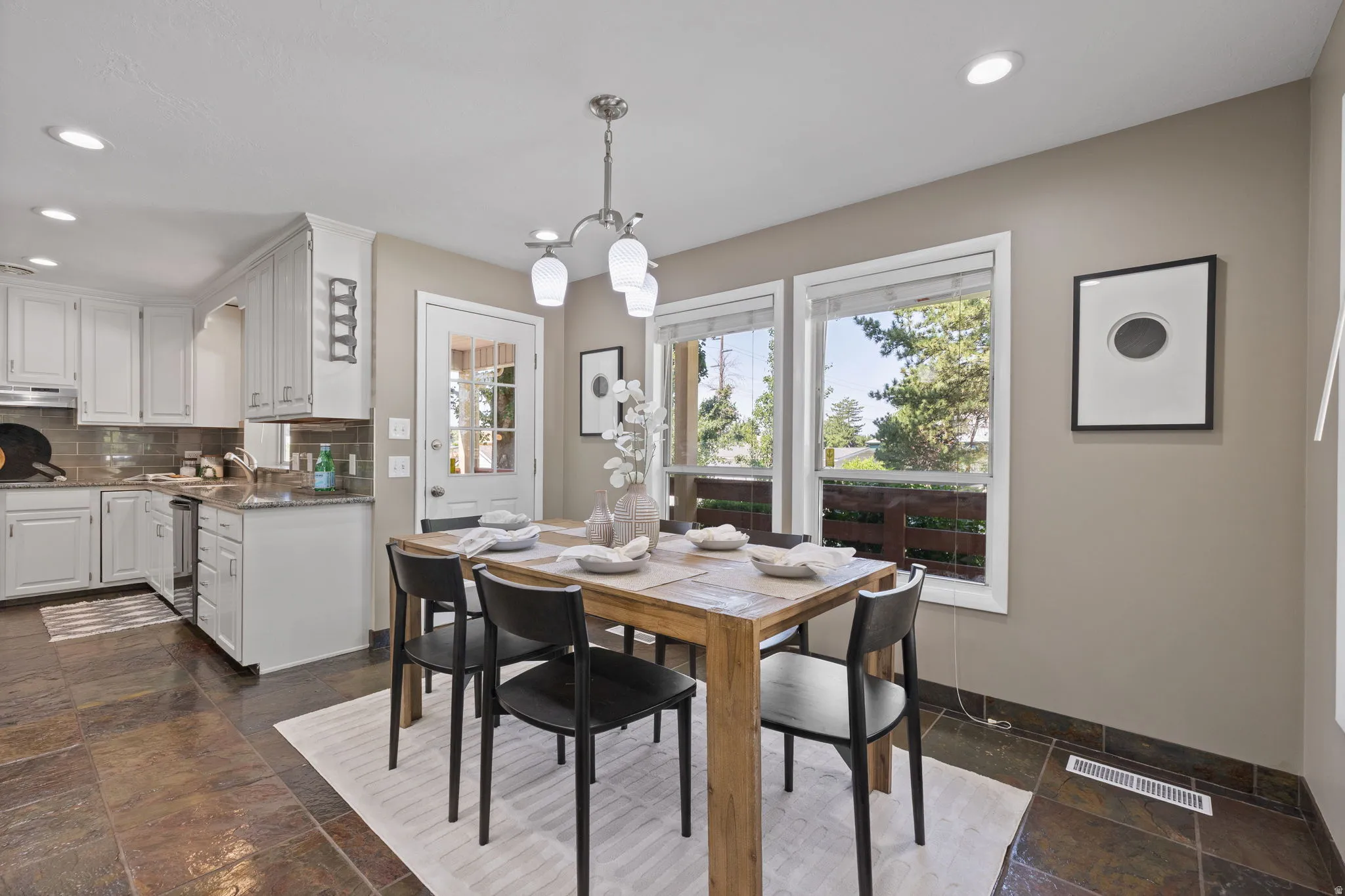 Dining area featuring a natural wood table, a multi-light chandelier, and three large windows