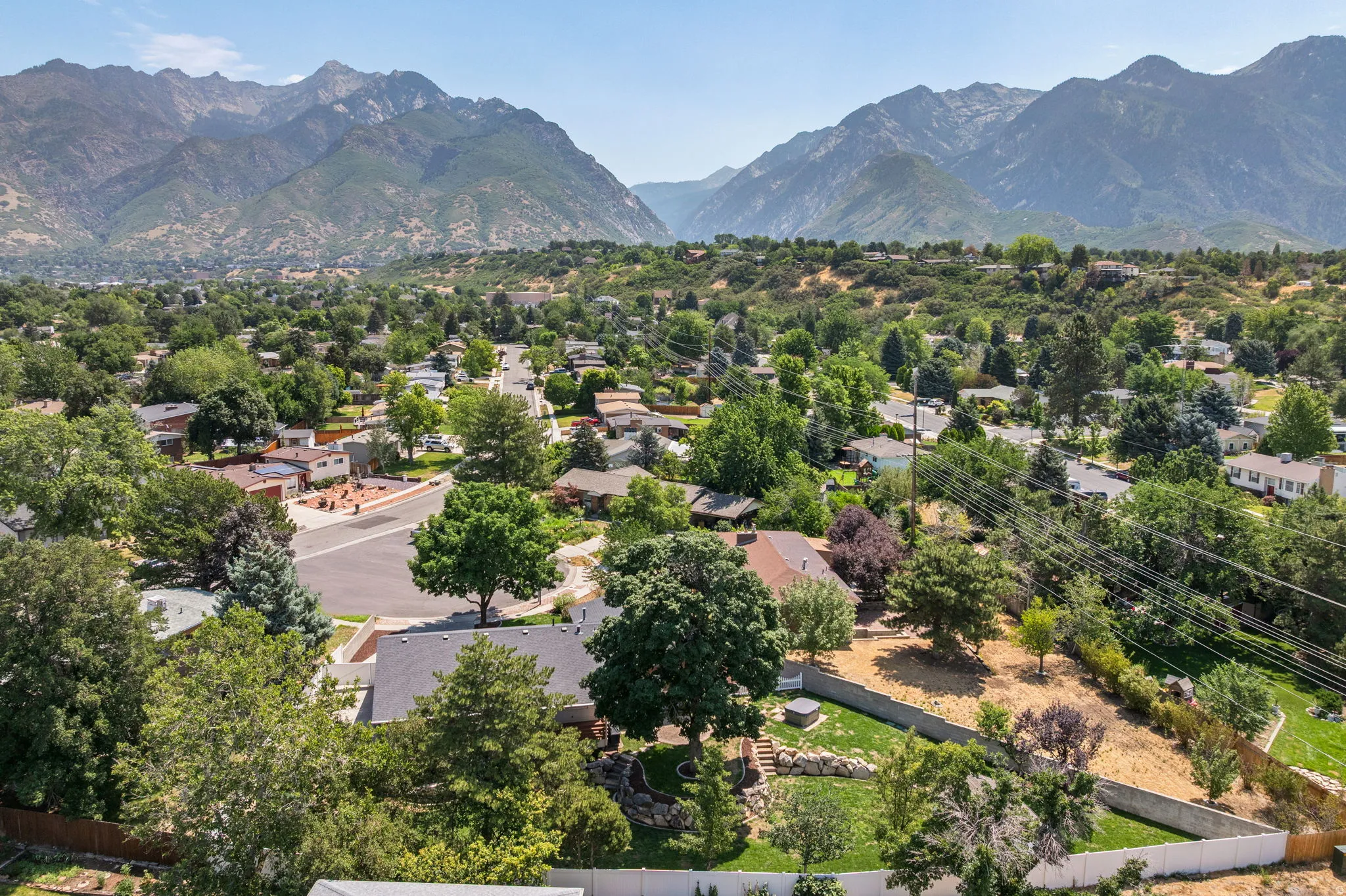 Mountain backdrop framing a residential area with mature trees and a clear sky