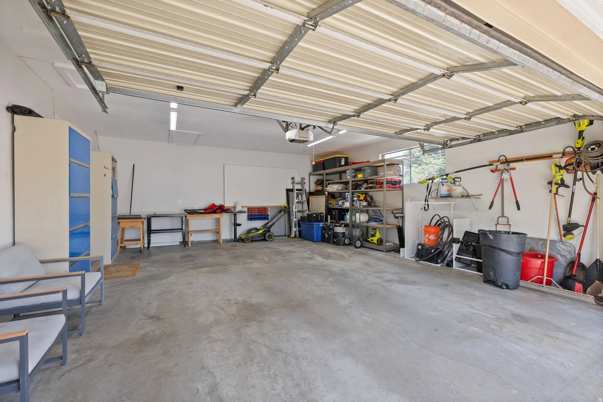 Spacious 2-car garage featuring a concrete floor, built-in shelving, and ample overhead lighting