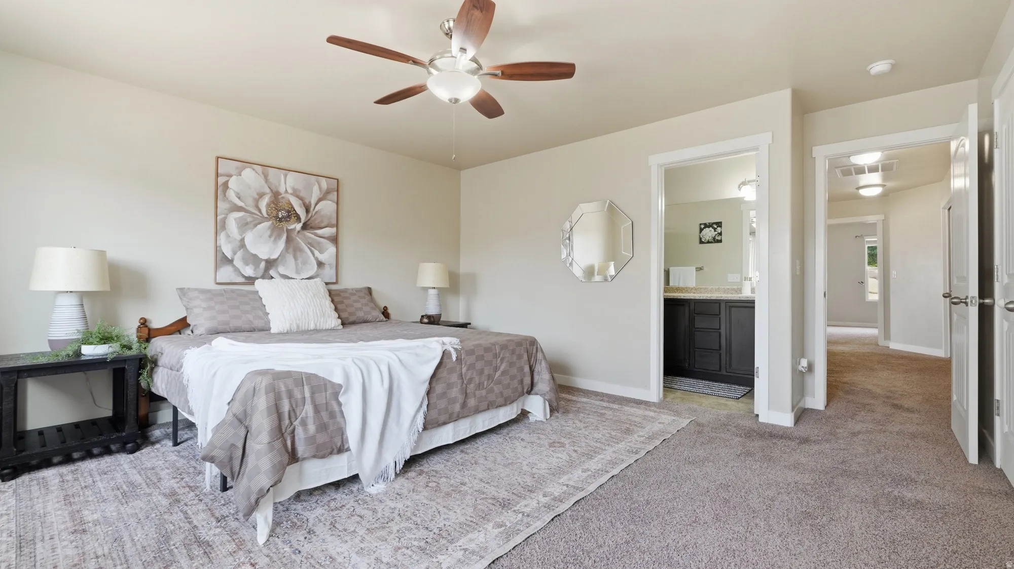Spacious carpeted bedroom with light-toned walls and a ceiling fan