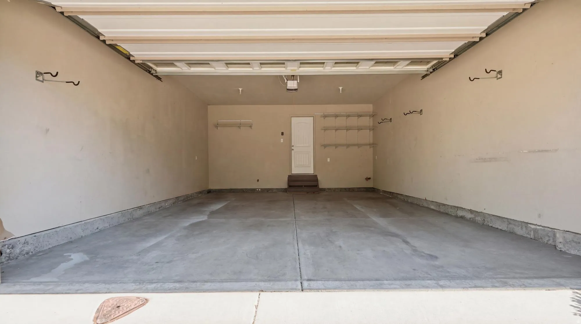 Spacious garage featuring a concrete floor, light-toned walls, overhead garage door track system, and built-in shelving units