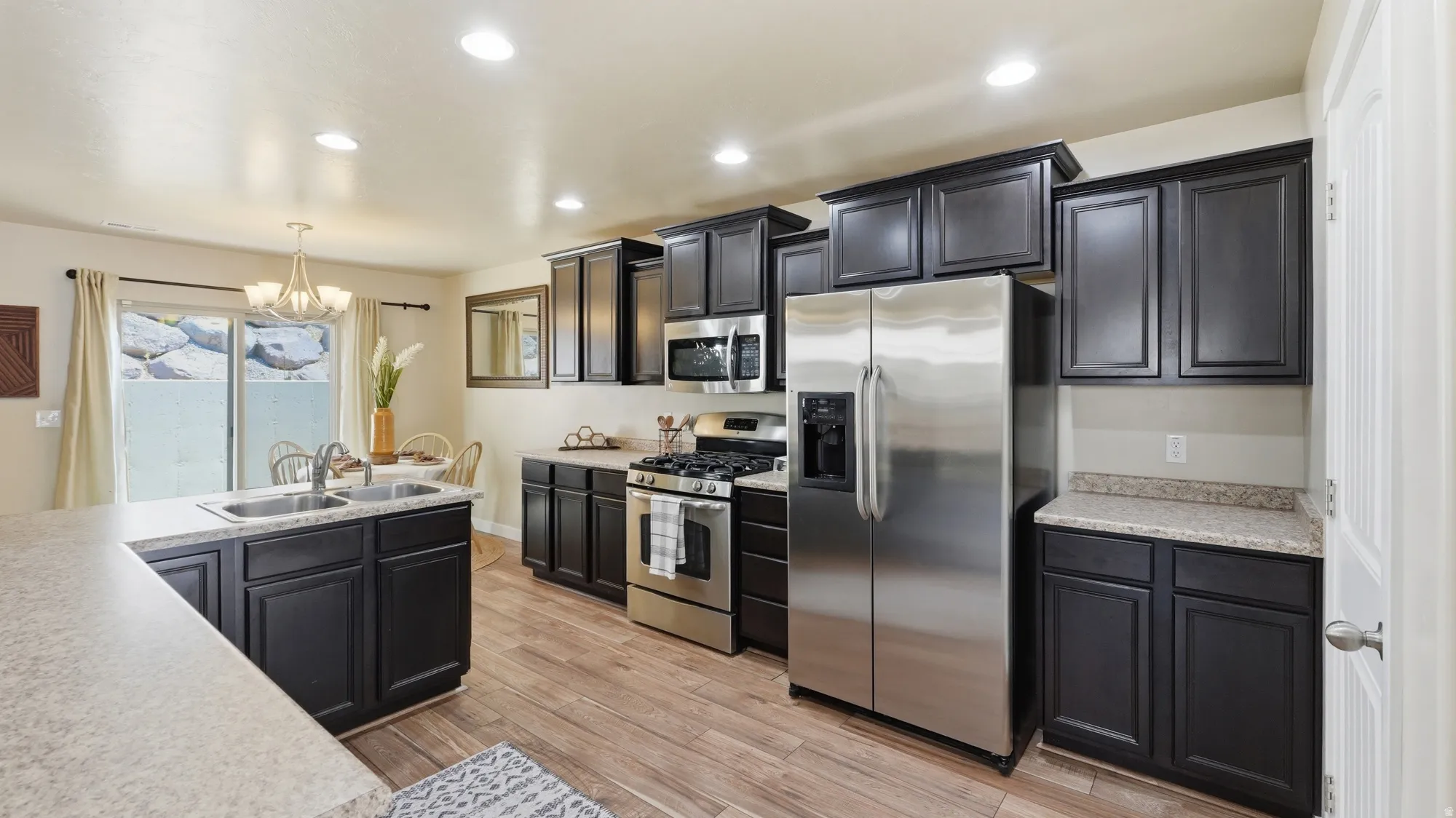 Modern kitchen featuring dark wood cabinetry, light-toned countertops, and stainless steel appliances