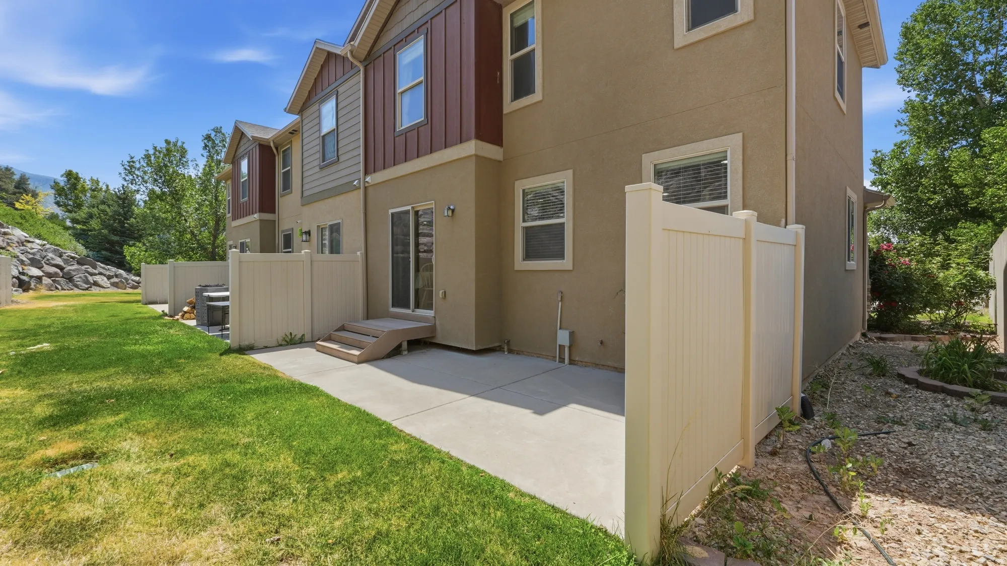 Rear exterior featuring a concrete patio, sliding glass door access, and multi-tone siding