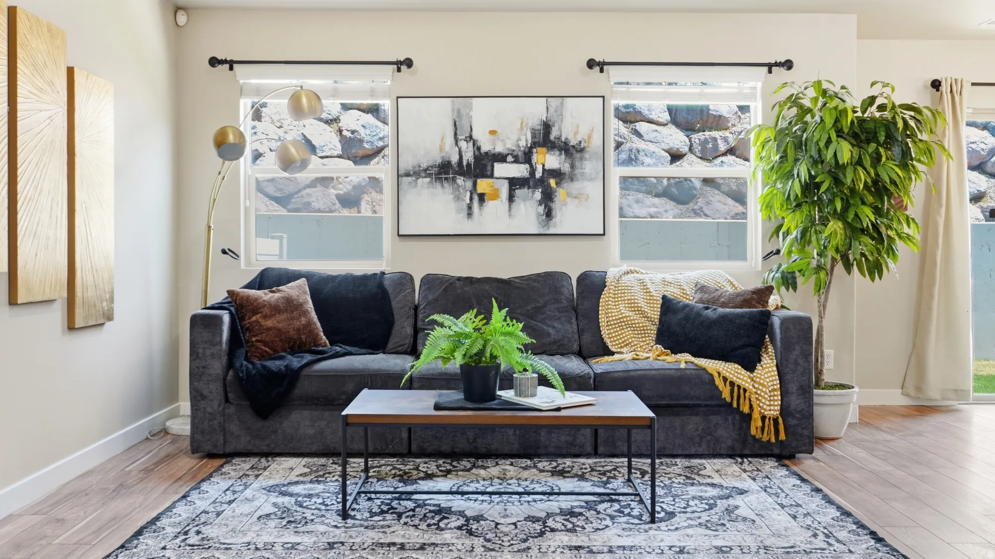Spacious living area featuring wood-finish flooring, light-toned walls, and multiple windows