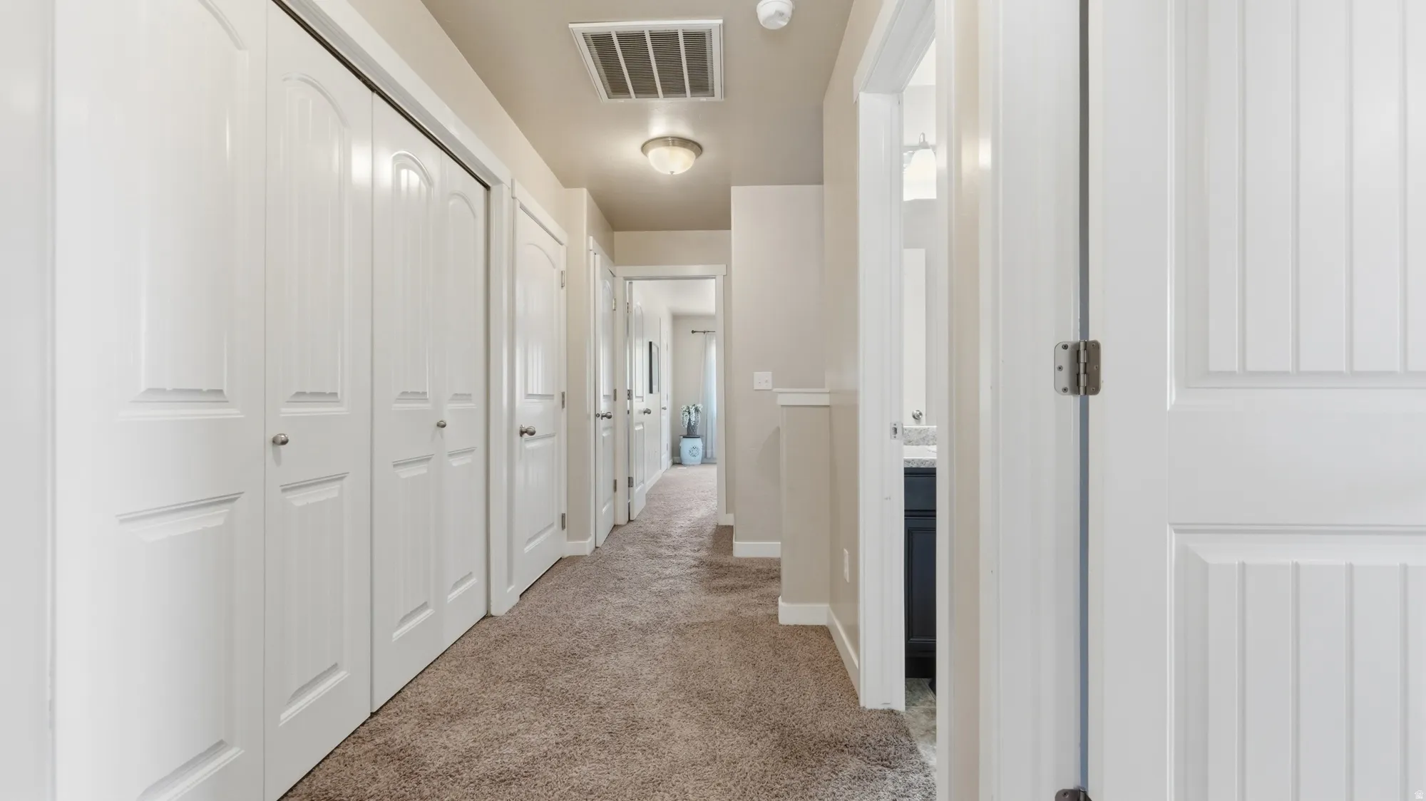 Hallway with neutral tone carpeting and light-colored walls
