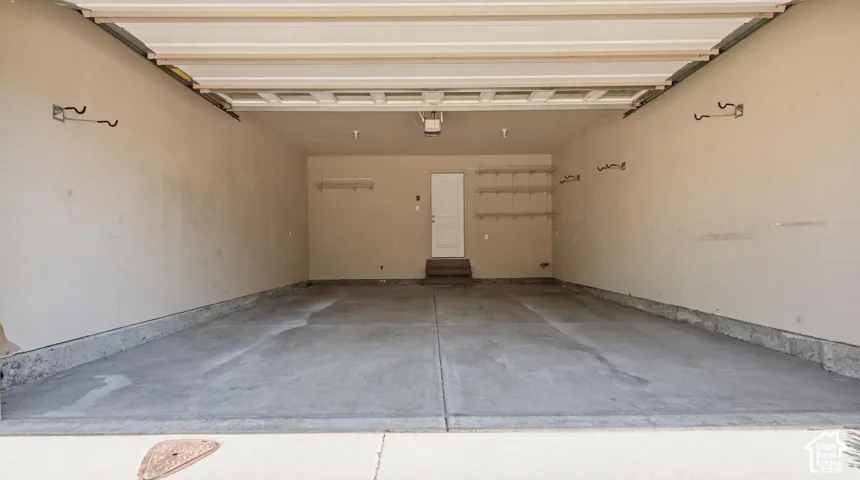 Spacious garage featuring a concrete floor, light-toned walls, overhead garage door track system, and built-in shelving units