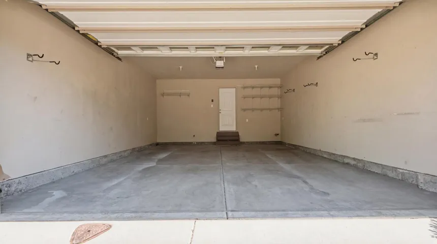 Spacious garage featuring a concrete floor, light-toned walls, overhead garage door track system, and built-in shelving units