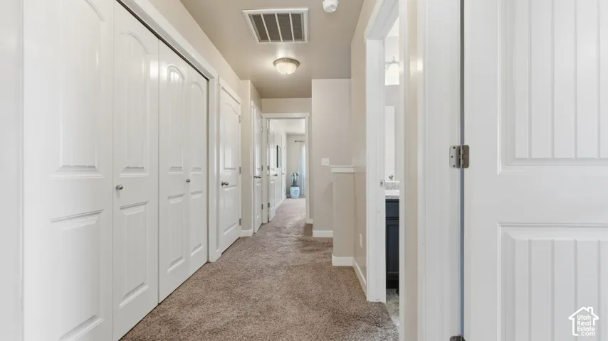 Hallway with neutral tone carpeting and light-colored walls