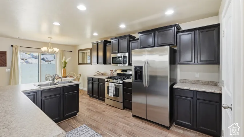 Modern kitchen featuring dark wood cabinetry, light-toned countertops, and stainless steel appliances