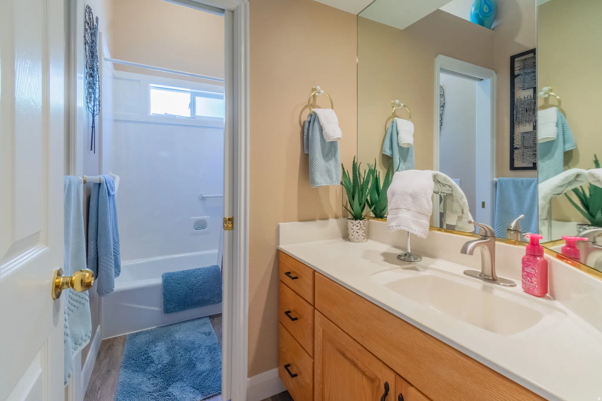Bathroom vanity featuring a single basin sink, brushed nickel faucet, and a light-toned countertop