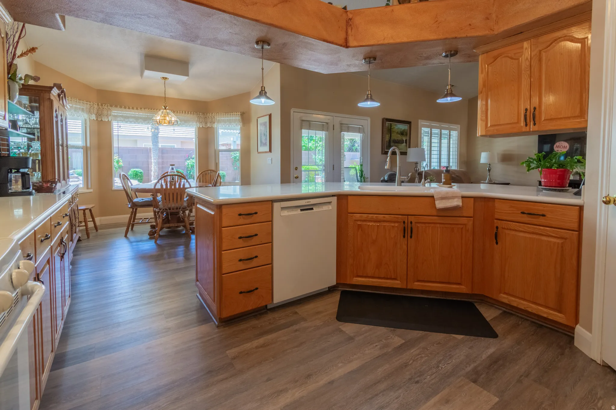 Kitchen featuring wood-finish flooring, light wood cabinetry, light-toned countertops, and a built-in dishwasher
