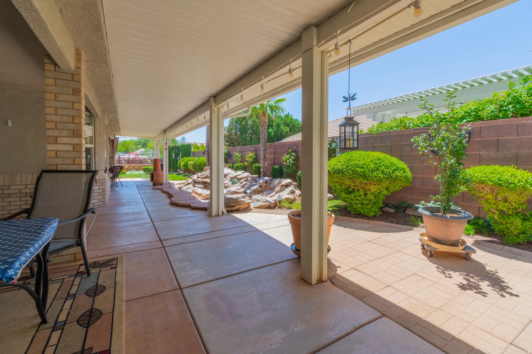 Expansive covered patio featuring a concrete slab, supporting columns, and overhead lighting