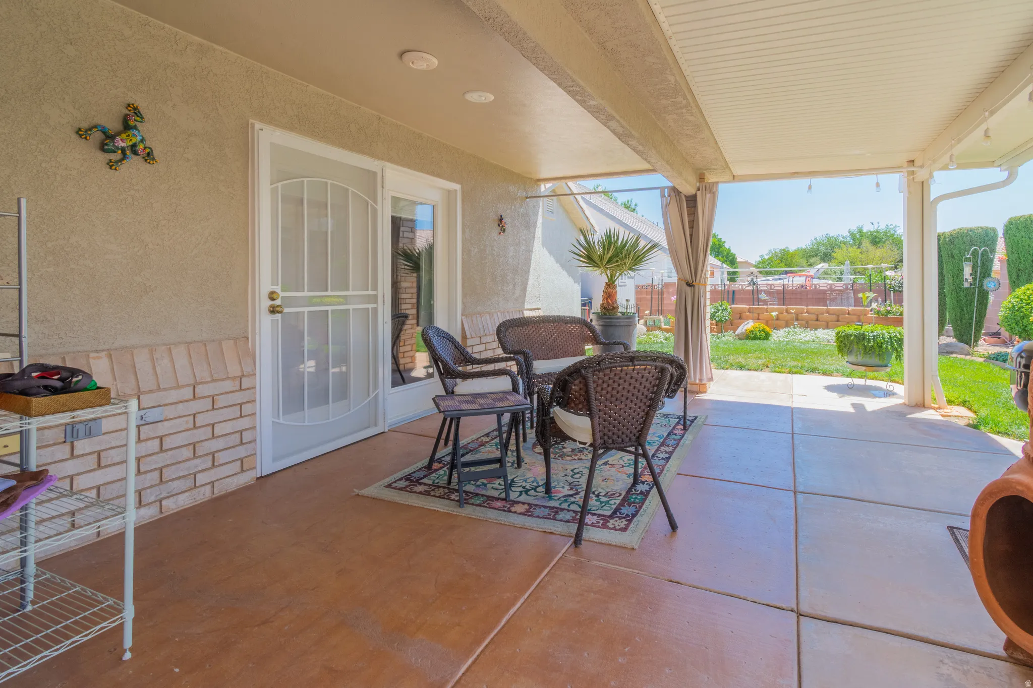 Covered patio featuring concrete flooring, a white metal security screen door, and a brick facade accent wall