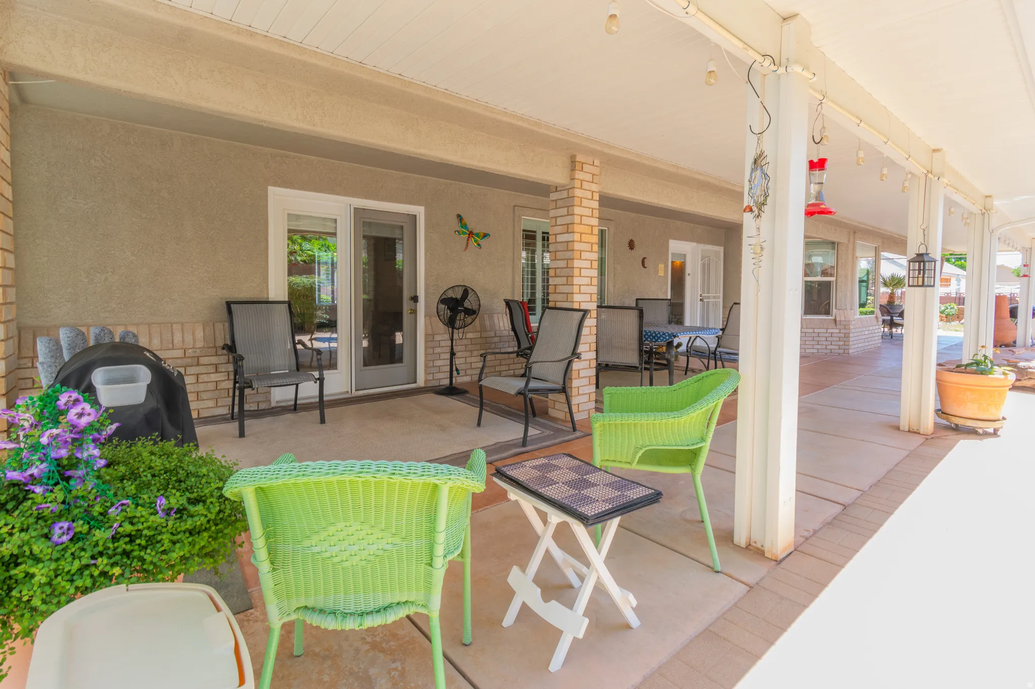 Expansive covered patio featuring stucco and brick veneer walls, concrete flooring, and multiple access points to the interior