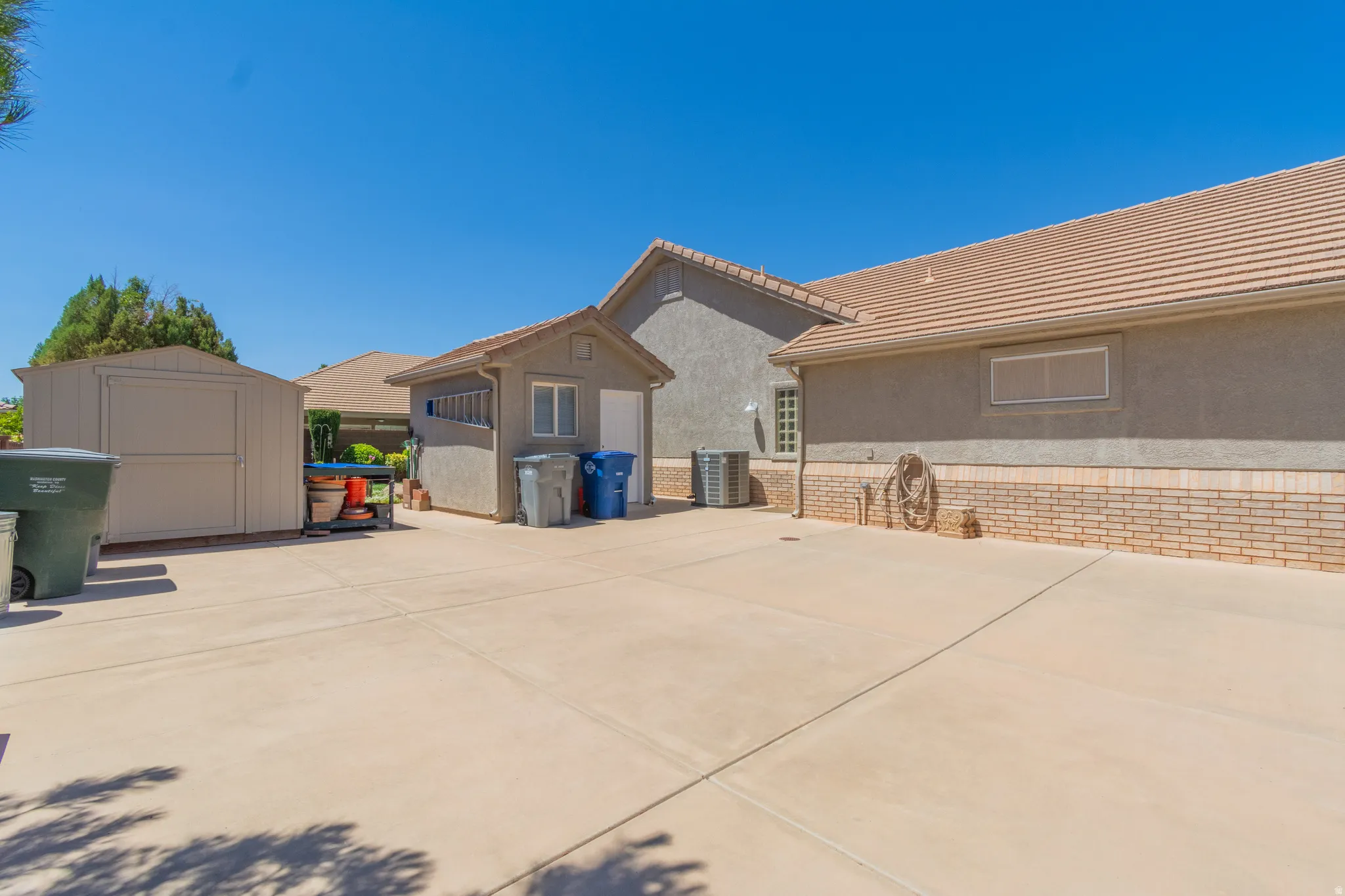 Expansive concrete driveway with a large freestanding storage shed and an additional detached utility structure