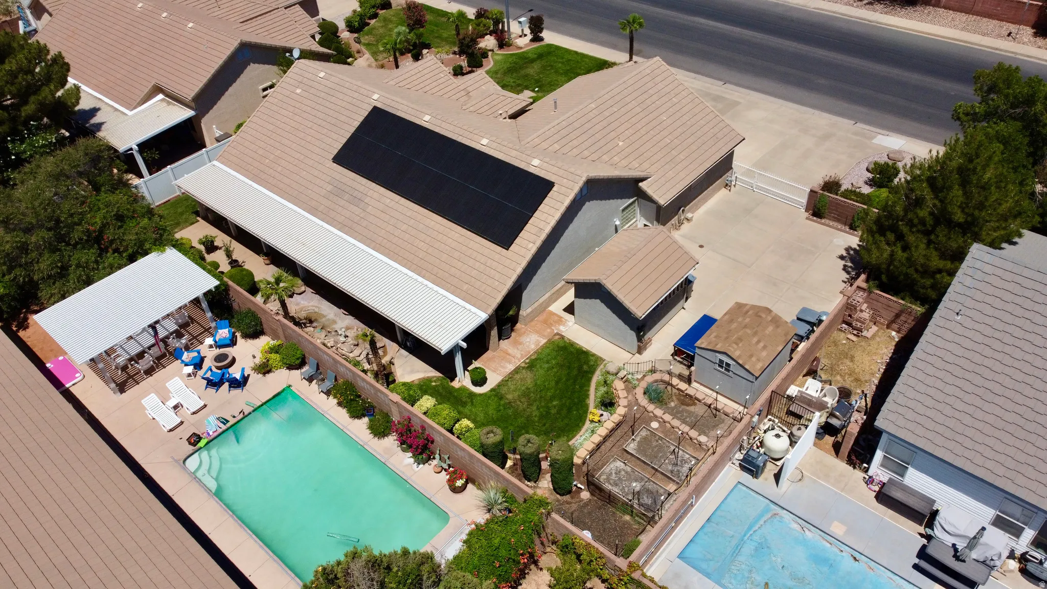 Rear exterior featuring a rectangular in-ground pool, covered patio, and a separate shaded pergola area