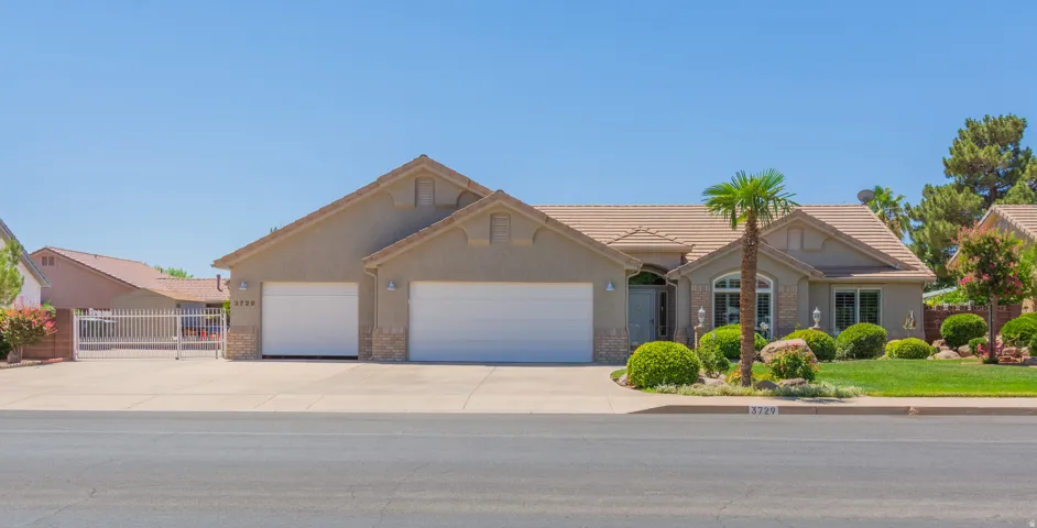 Stucco exterior residence featuring a tile roof, an arched front window, and a two-car garage