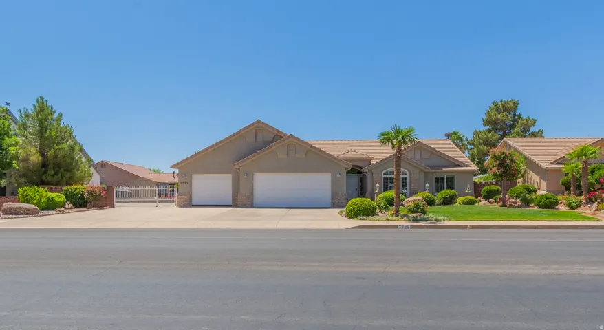Single-story residence featuring a stucco exterior with stone accents, a two-car garage, and a manicured front lawn