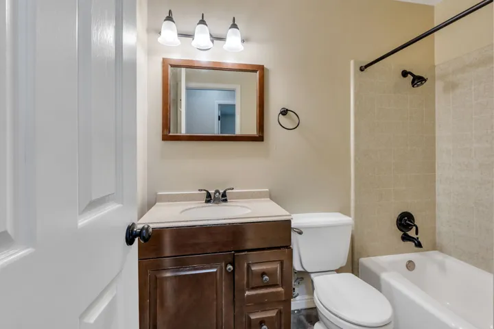 Wood-finish vanity with a light-toned countertop, integrated sink, and dual-handle faucet