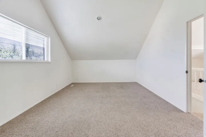 Vaulted ceiling room featuring carpet flooring and a window with blinds