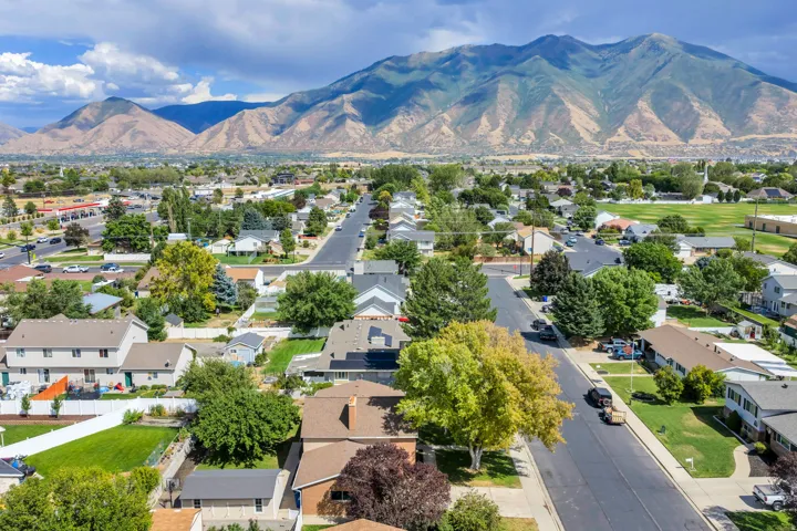 Residential neighborhood with mature trees, mountain backdrop, and paved streets