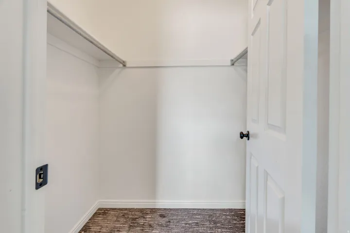 White paneled door with matte black hardware, integrated hanging rod, wood-finish flooring, and crisp white walls