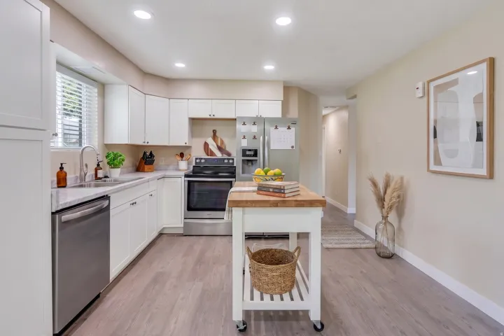 Kitchen featuring white cabinetry, stainless steel appliances, light-toned countertops, wood-finish flooring, and recessed lighting
