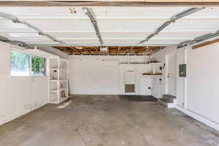 Spacious garage featuring a concrete floor, built-in shelving, and a pedestrian door