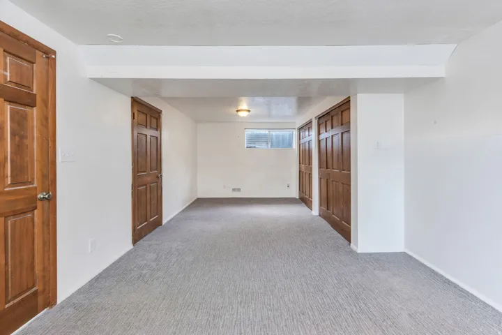Spacious room featuring light-colored carpeting and white walls