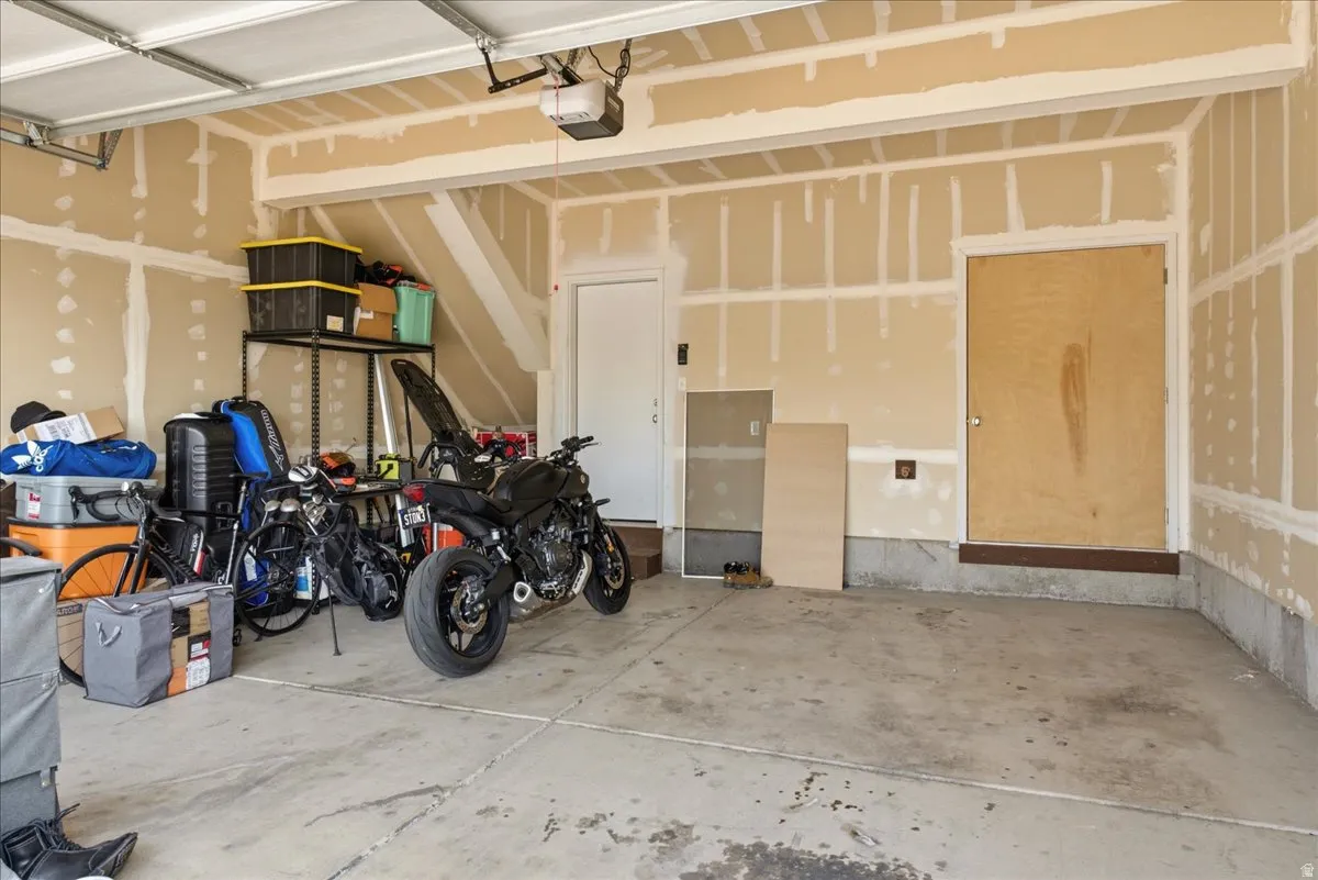 Spacious garage featuring a concrete floor, an overhead garage door opener, and multiple access doors