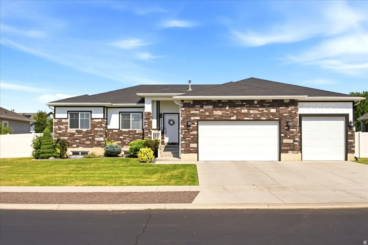Single-story residence featuring a dark shingle roof, stone and horizontal siding exterior, attached two-car garage, and a concrete driveway