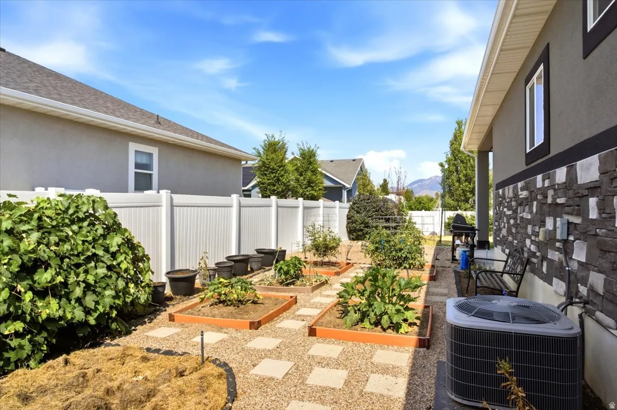 Backyard featuring raised garden beds, gravel pathways with square stepping stones, and a privacy fence
