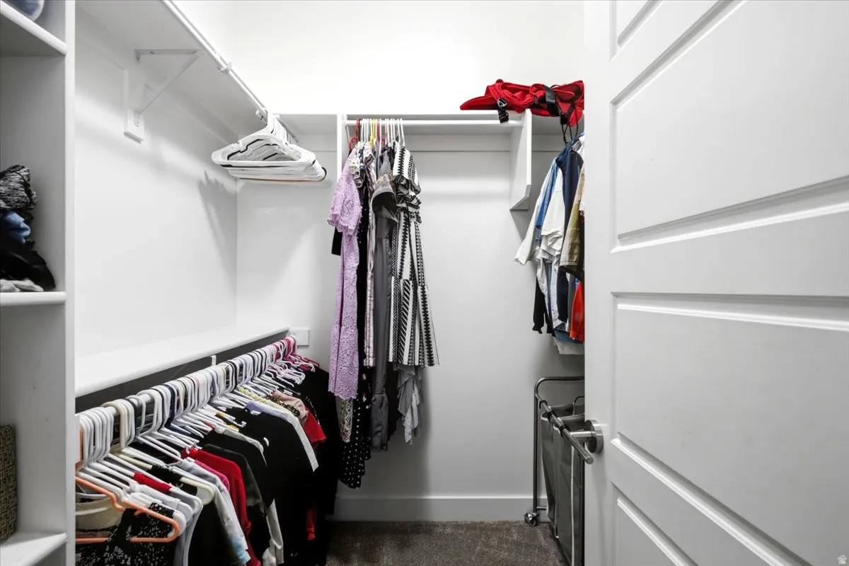 Walk-in closet featuring white built-in shelving, multiple hanging rods, and a paneled white door