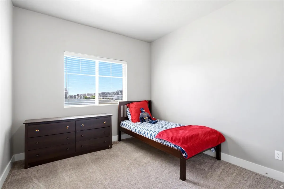 Bright room featuring a large window, neutral wall paint, and light-toned carpet flooring
