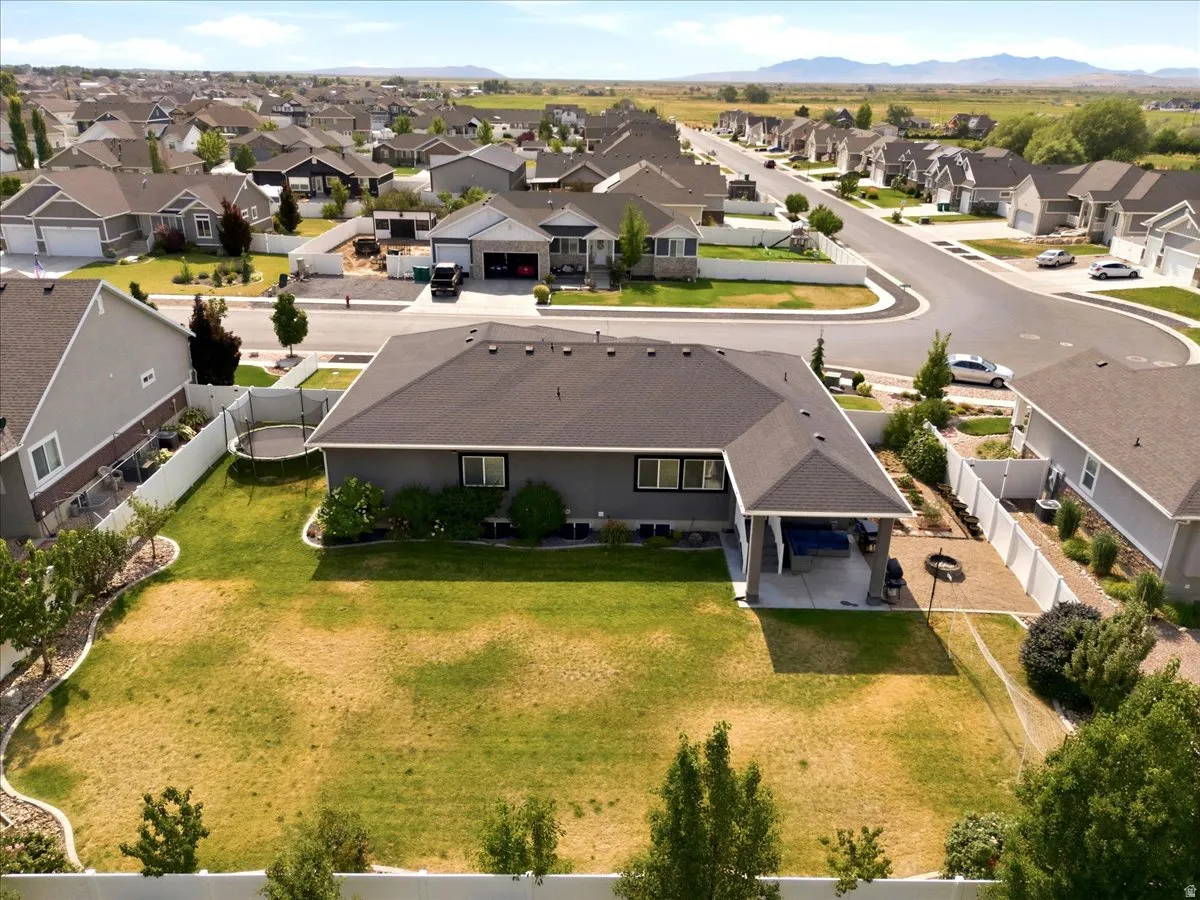 Expansive rear yard with a covered patio, paved hardscaping, and mature landscaping
